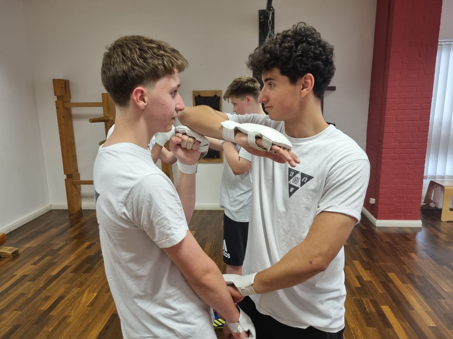 Zwei Jugendliche stehen sich beim Partnertraining gegenüber und führen eine Technik aus.