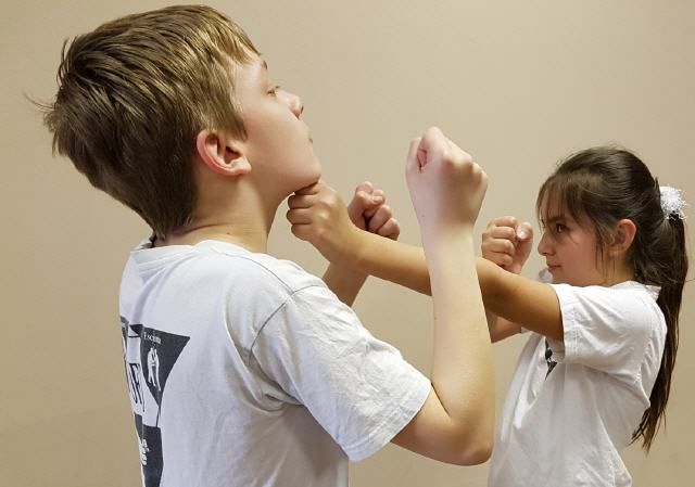 Mädchen übt Verteidigungstechnik gegen Jungen im Wing Tsun Kindertraining