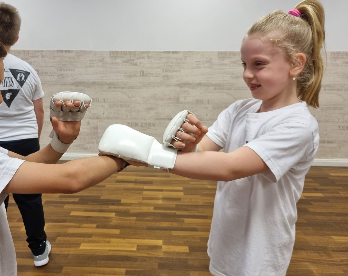 Ein Mädchen mit Boxhandschuhen übt eine Schlagtechnik an einem Partner in der Kampfsportschule.